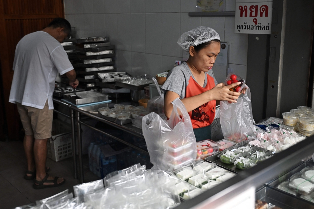 Desserts being packed in single-use plastic containers and bags at a traditional Thai dessert shop in Bangkok. (Photo by Lillian Suwanrumpha / AFP)
