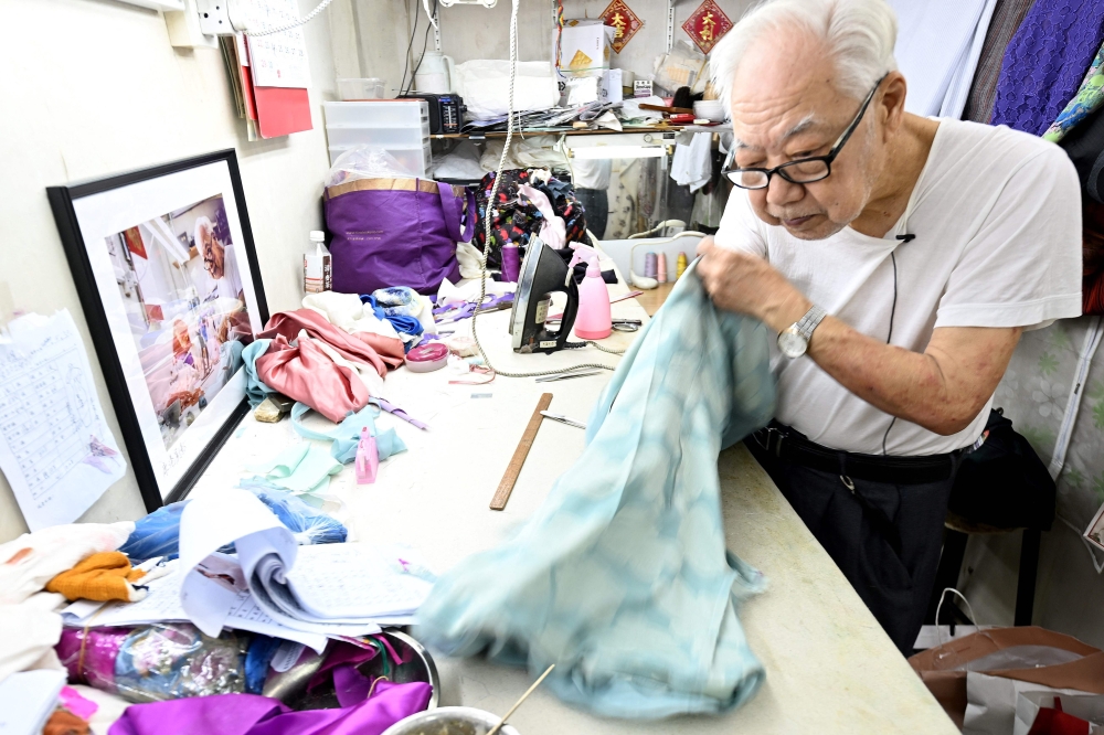 This Photo taken on September 5, 2024 shows Cheongsam master Yan Kar-man working in his small workshop in Kowloon, Hong Kong. (Photo by Peter Parks / AFP) 