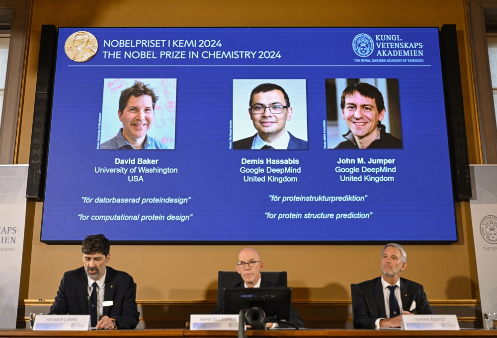 (Bottom L-R) Chair of the Nobel Prize Committee for Chemistry Heiner Linke, Secretary General of the Royal Swedish Academy of Sciences Hans Ellegren and Member of the Nobel Prize Committee for Chemistry Johan Aqvist announce the laureates of the 2024 Nobel Prize in Chemistry, (On screen L-R) David Baker, Demis Hassabis and John M Jumper, at the Royal Swedish Academy of Sciences in Stockholm, Sweden on October 9, 2024. (Photo by Jonathan Nackstrand / AFP)