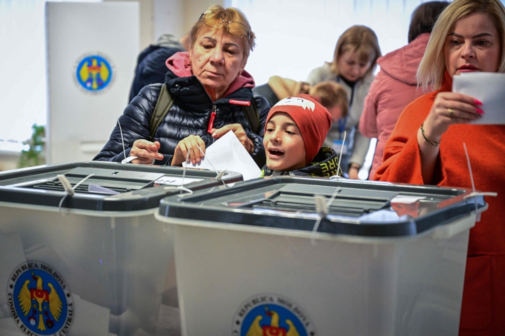 Voters cast their ballots for the presidential election and referendum on joining the European Union at a polling station in Chisinau on October 20, 2024. (Photo by Daniel Mihailescu / AFP)