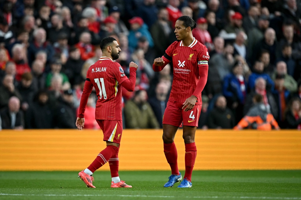 Liverpool's Egyptian striker #11 Mohamed Salah celebrates scoring the team's first goal with Liverpool's Dutch defender #04 Virgil van Dijk on October 20, 2024. (Photo by Paul Ellis / AFP)

