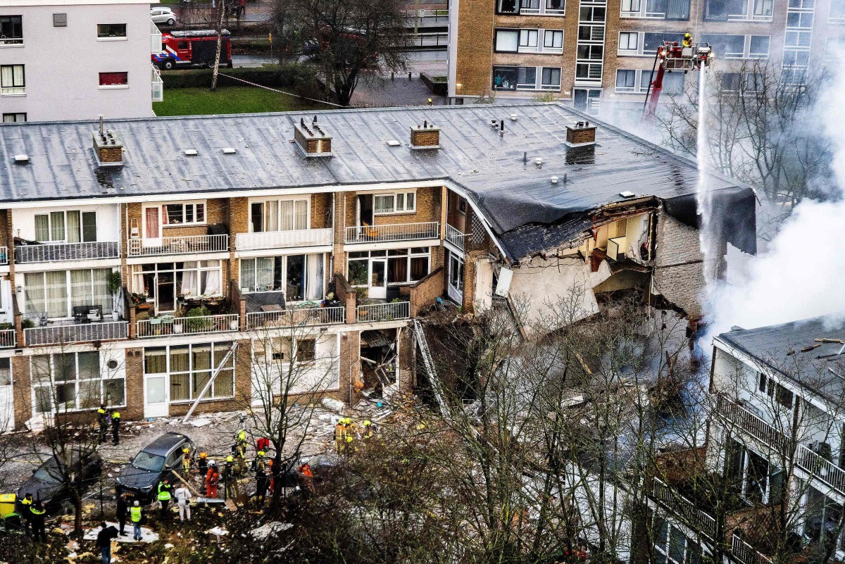 Firemen try to douse a fire following a fire and an explosion at a residential building in The Hague on December 7, 2024. A three-storey apartment block in the Hague partially collapsed December 7, 2024 after a fire and explosion, firefighters said, with first responders searching for people under the rubble. (Photo by Jeffrey GROENEWEG / ANP / AFP) / Netherlands OUT
