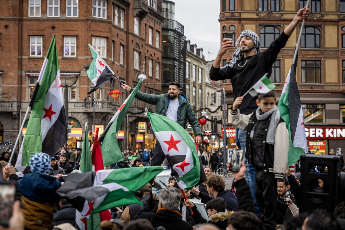 Members of the Syrian community wave Syrian flags on December 8, 2024 in Copenhagen, Denmark, as they rally to celebrate the end of Bashar al-Assad's rule after rebel fighters took control of the Syrian capital Damascus overnight. (Photo by Emil Nicolai Helms / Ritzau Scanpix / AFP) / Denmark OUT
