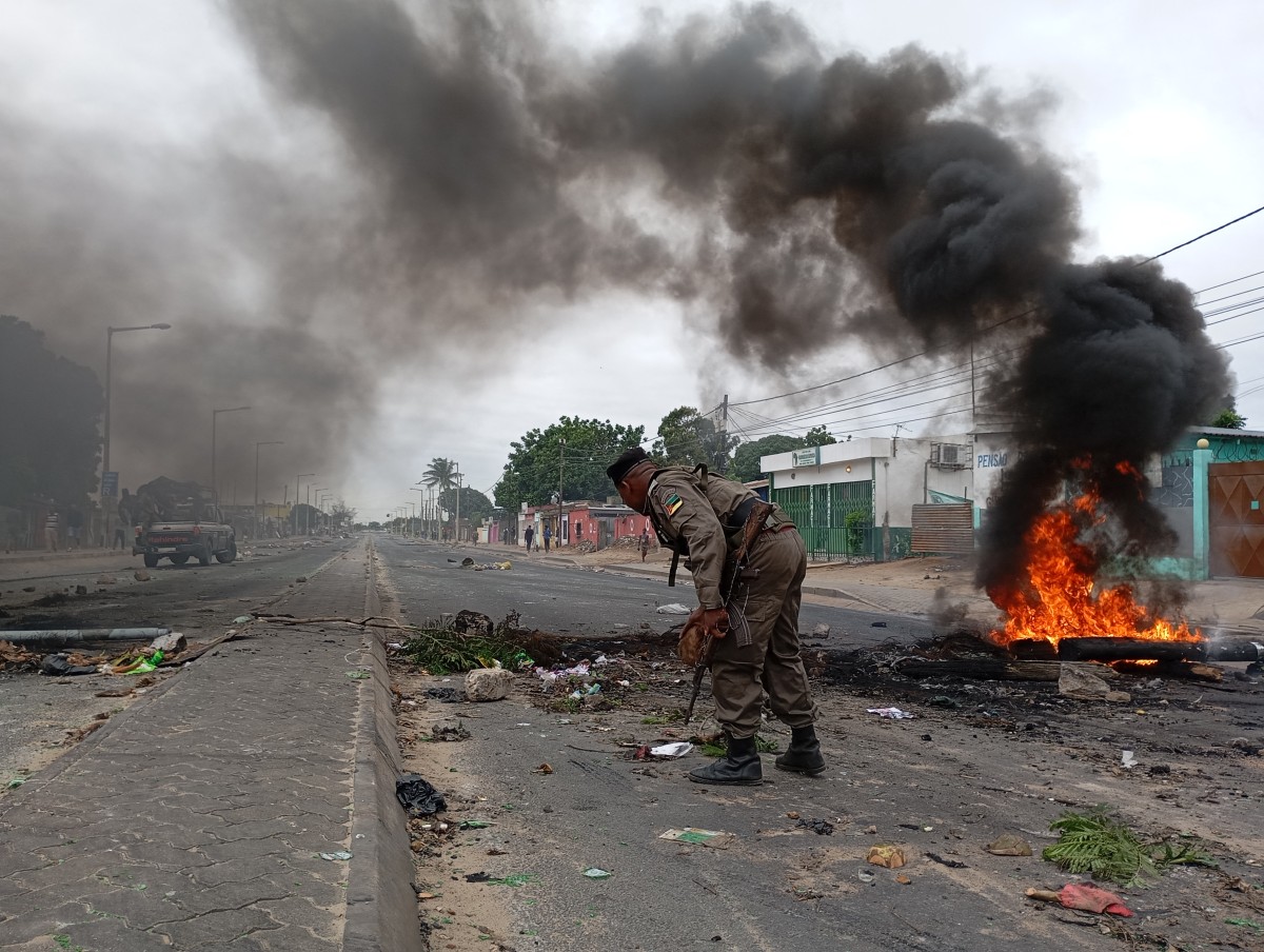 Mozambican security forces are seen next to a burning barricade in Maputo on December 24, 2024. (Photo by Amilton Neves / AFP)
