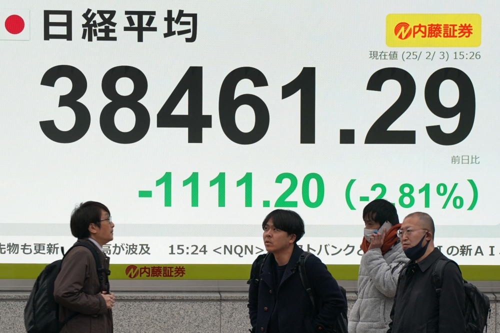 Pedestrians stand in front of of an electronic board showing the numbers of the Nikkei Stock Average on the Tokyo Stock Exchange on a street in central Tokyo on February 3, 2025. (Photo by Kazuhiro Nogi / AFP)
