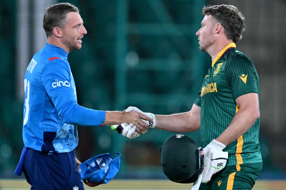 England's captain Jos Buttler (L) and South Africa's David Miller shake hands at the end of the ICC Champions Trophy one-day international in Karachi on March 1, 2025. (Photo by Asif Hassan / AFP)
