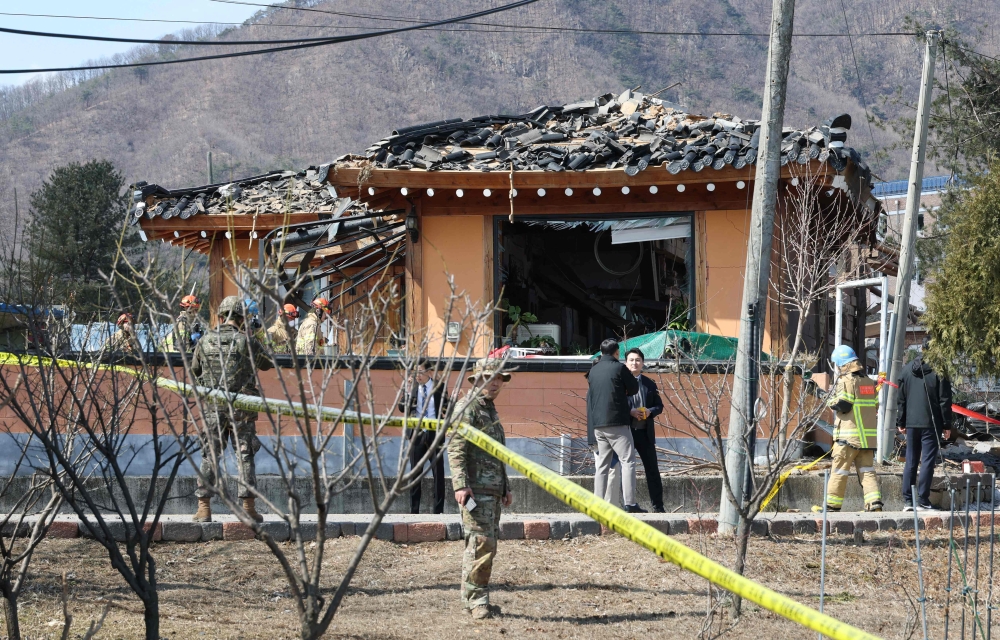 South Korean soldiers and rescue workers inspect a damaged house after a bomb accident at a village in Pocheon on March 6, 2025. (Photo by YONHAP / AFP) 