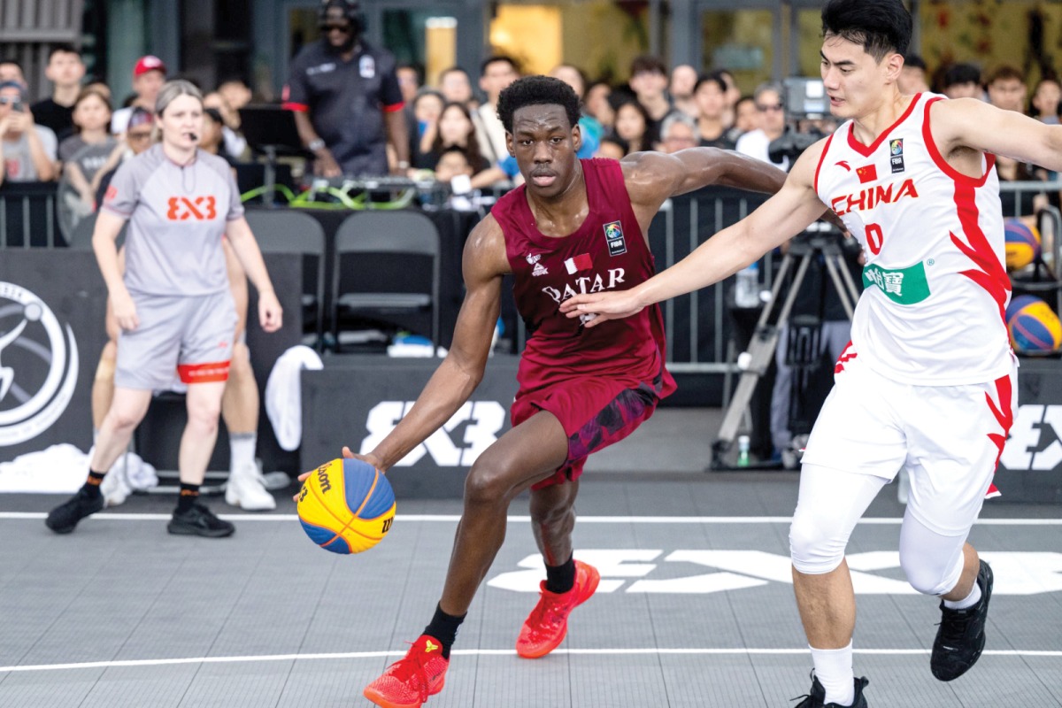 Qatar's Mohammed Hashem (left) dribbles during the game against China.