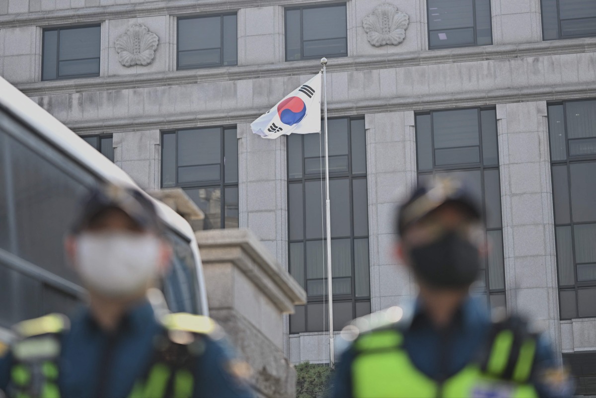 Police officers stand a road in Seoul on April 1, 2025 in front of the Constitutional Court, which will issue its long-awaited ruling on President Yoon Suk Yeol's impeachment on April 4, months after he was suspended for declaring martial law. (Photo by Pedro Pardo / AFP)