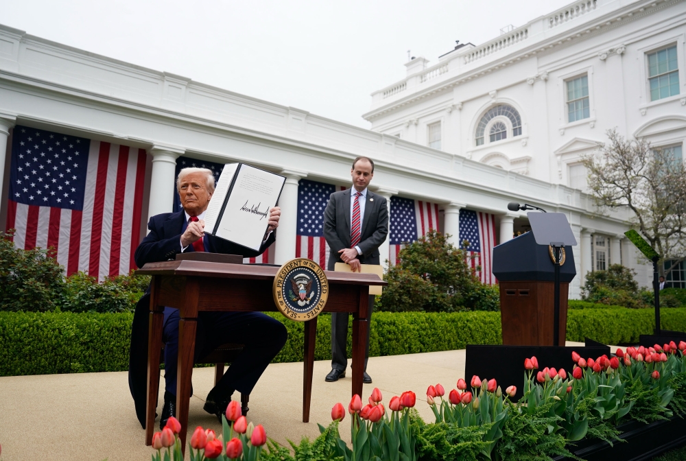 President Donald Trump displays an executive order after announcing a plan for tariffs on imported goods on Wednesday with staff secretary Will Scharf watching. (Photo by Jabin Botsford/The Washington Post)

