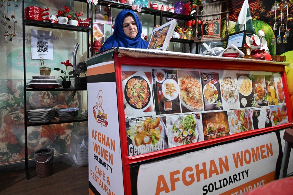 This picture taken on April 3, 2025 shows Afghan Citizen Cards (ACC) holder Benazir Raufi at the counter of her restaurant in Rawalpindi. (Photo by Aamir Qureshi / AFP) 