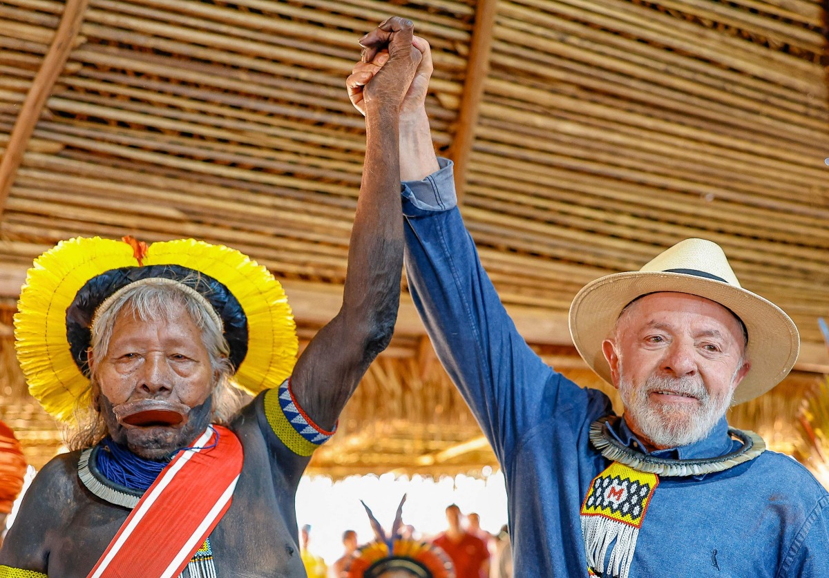 This handout picture released by the Brazilian Presidency shows Brazil's President Luiz Inacio Lula da Silva (R) and Indigenous leader of the Kayapo people Raoni Metuktire holding hands as they pose for a photograph during a meeting at the Piaracu village in the state of Mato Grosso, Brazil, on April 4, 2025. (Photo by Ricardo STUCKERT / BRAZILIAN PRESIDENCY / AFP)
