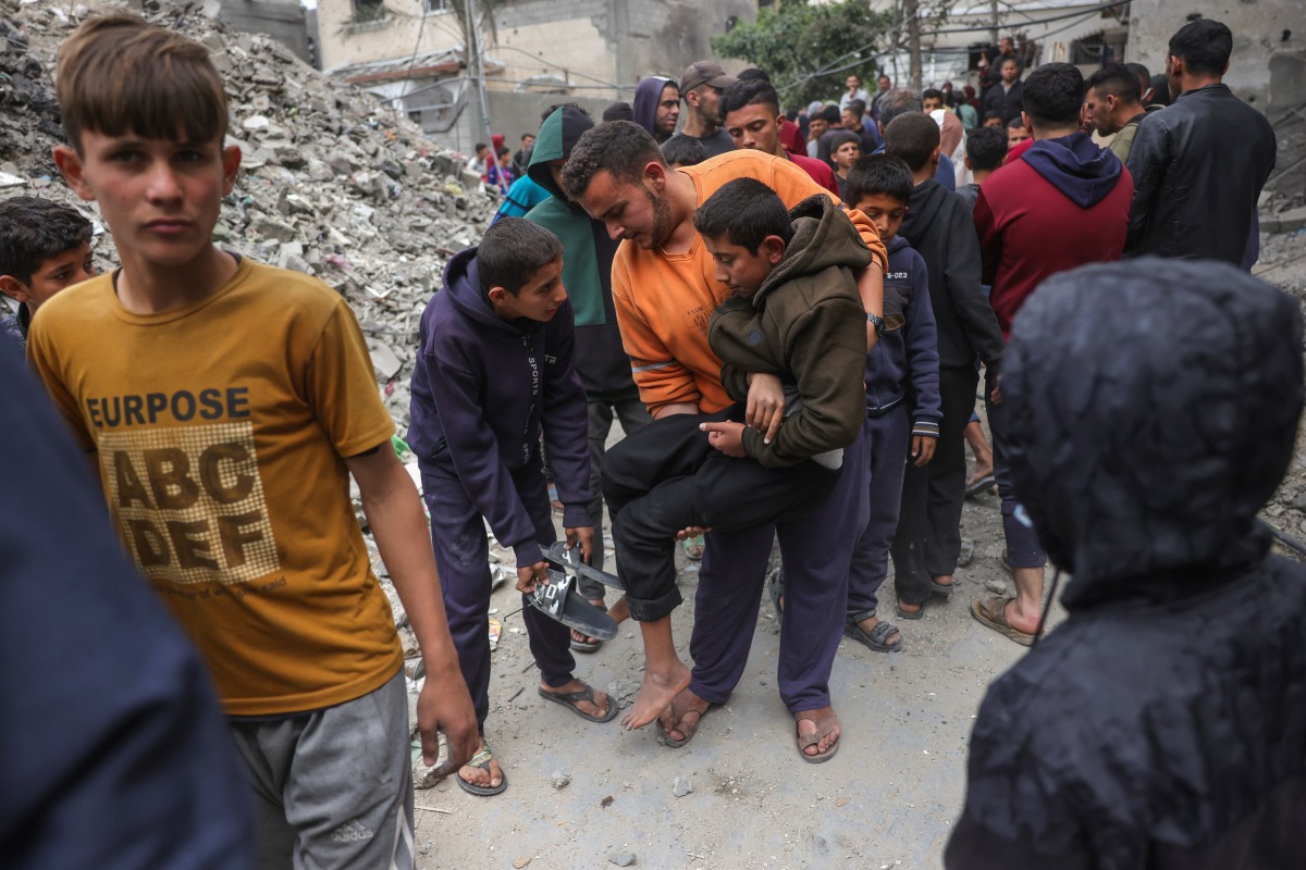 Palestinians help an injured man after an Israeli strike on the Manoun family home in Jabalia in the northern Gaza Strip on April 13, 2025. Photo by BASHAR TALEB / AFP.