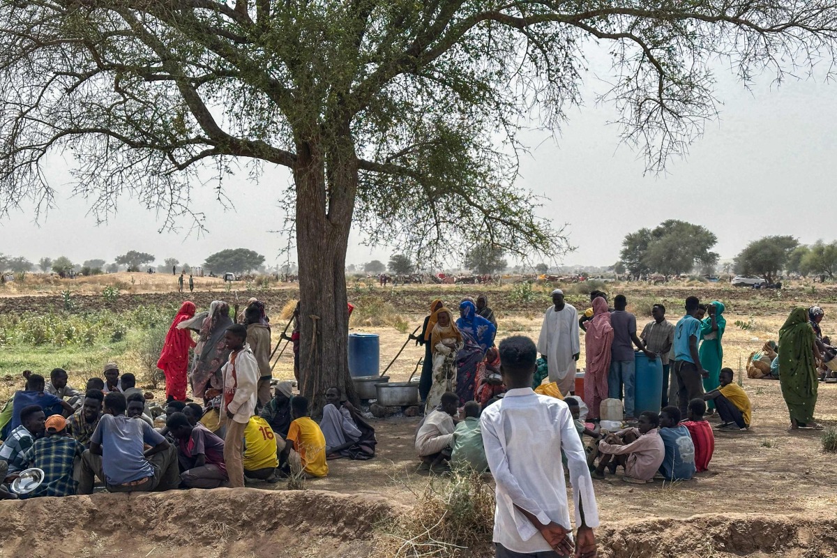 People who fled the Zamzam camp for the internally displaced after it fell under RSF control, gather for communal cooking in a makeshift encampment in an open field near the town of Tawila in war-torn Sudan's western Darfur region on April 13, 2025. (Photo by AFP)
