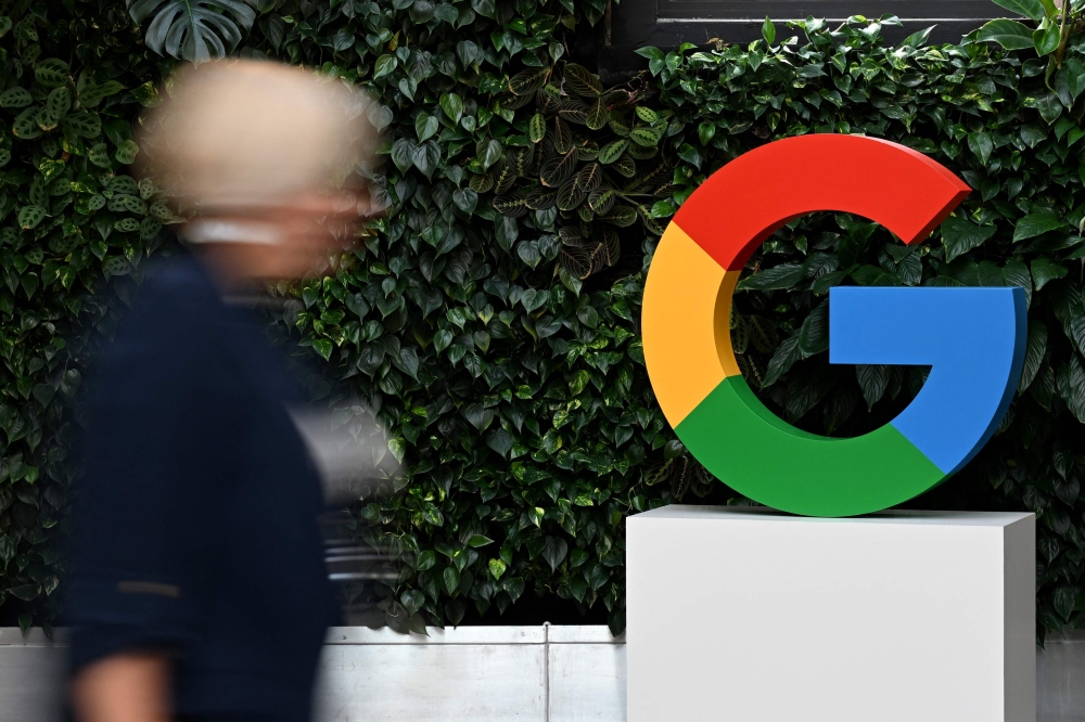 (Files) A woman walks past a Google logo at the Google Campus in Warsaw on February 13, 2025. (Photo by Sergei Gapon / AFP)