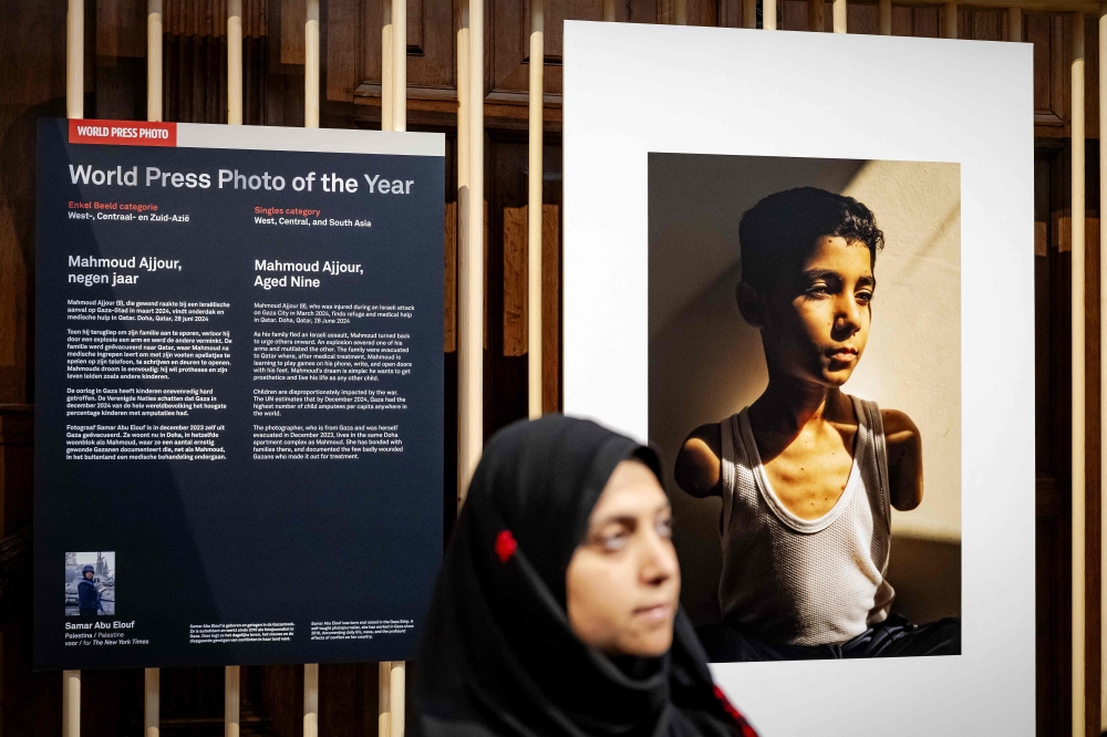 World Press Photo of 2025 award winner Samar Abu Elouf poses next to her winning photograph depicting a nine-year-old Palestinian boy who lost both arms during an Israeli attack on Gaza City at the Nieuwe Kerk in Amsterdam on April 17, 2025. (Photo by Robin van Lonkhuijsen / ANP / AFP) 