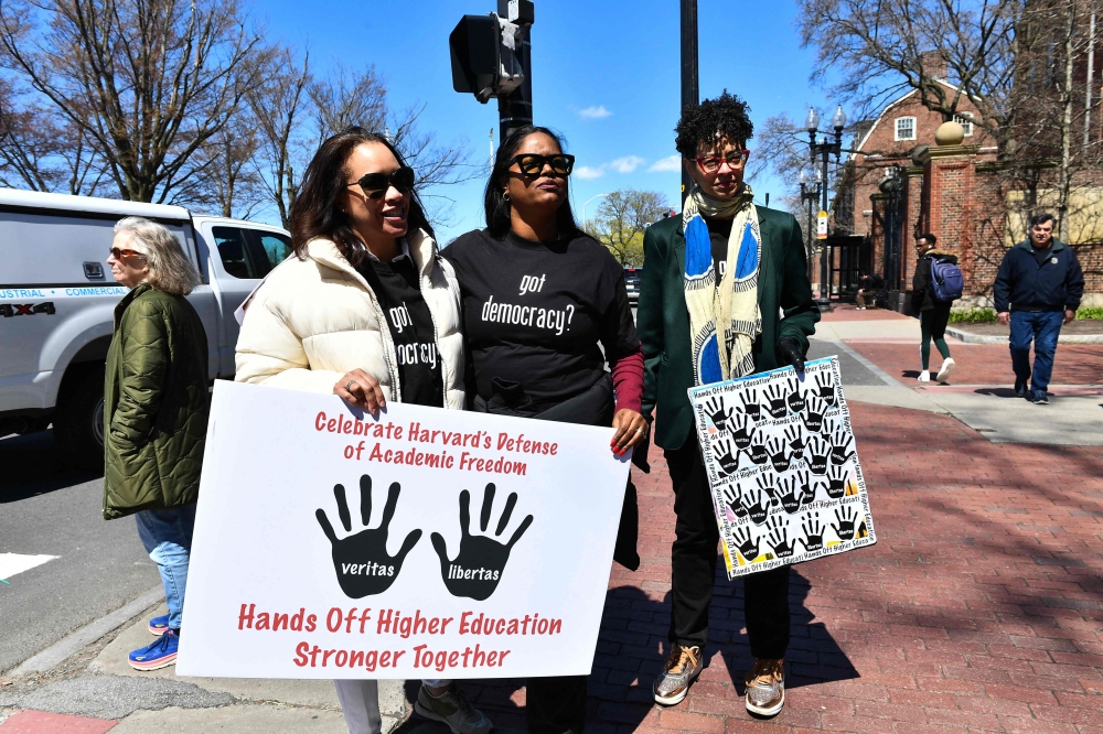 Demonstrators stand around the John Harvard Statue in Harvard Yard after a rally was held against President Donald Trump's attacks on Harvard University at Harvard University in Cambridge, Massachusetts on April 17, 2025. (Photo by Joseph Prezioso / AFP)
