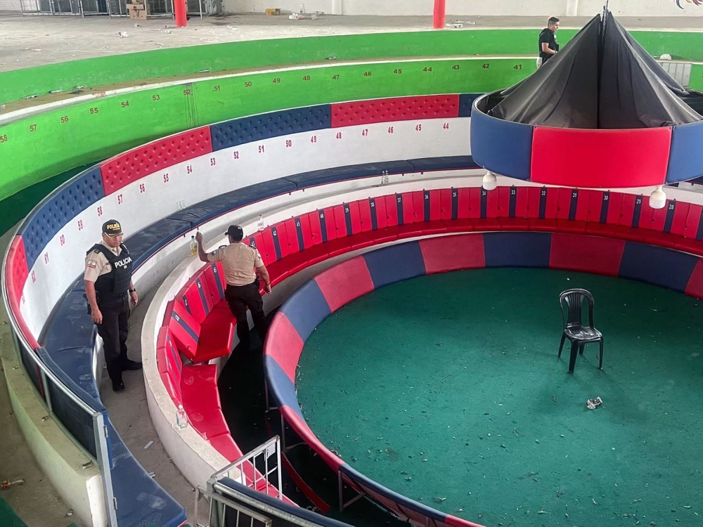 This handout picture released by the Ecuadorian Police shows members of the police checking the Coliseo de Gallos Fortaleza in the rural community of La Valencia in El Carmen Canton, Manabi Province, Ecuador, on April 18, 2025, where an armed attack took place the night before. (Photo by Handout / Ecuadorian Police / AFP) 