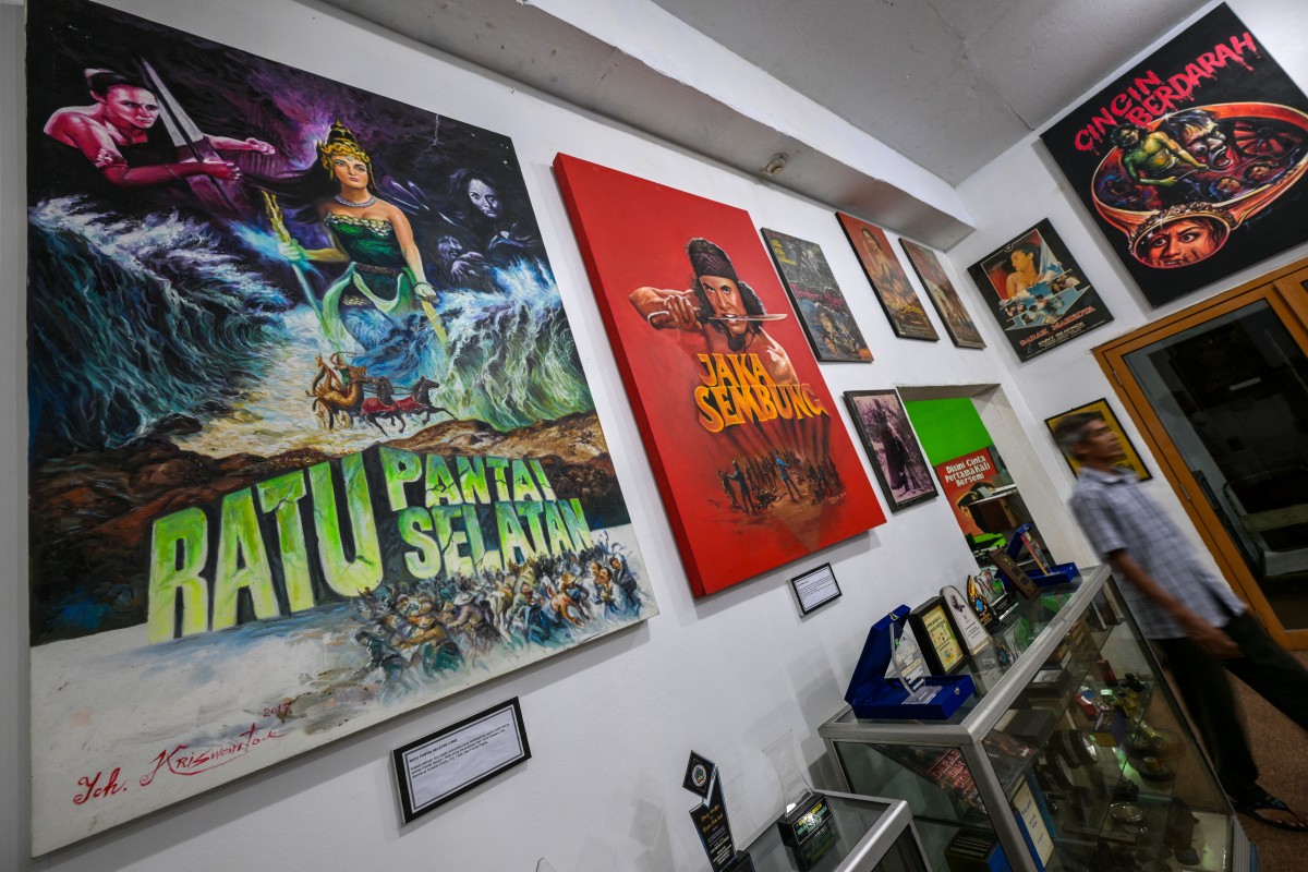A man walks past horror movie posters titled 'Queen of the Southern Sea' and 'The Bloody Ring' at the Usmar Ismail Film Center in Jakarta on April 11, 2025. (Photo by Bay Ismoyo / AFP) 
