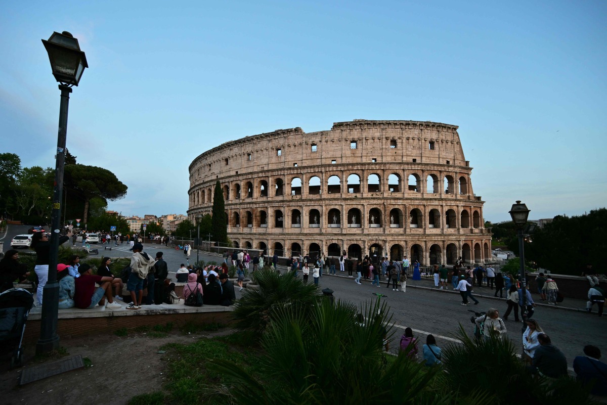 Visitors walk past the Colosseum, a day after the Pope's death, in Rome on April 22, 2025. (Photo by Andrej ISAKOVIC / AFP)
