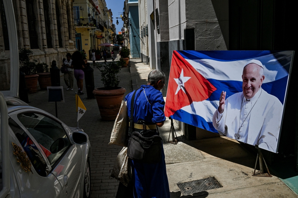 A man walks near a picture of the late Pope Francis on a street in Havana on April 22, 2025. (Photo by Yamil Lage / AFP)
