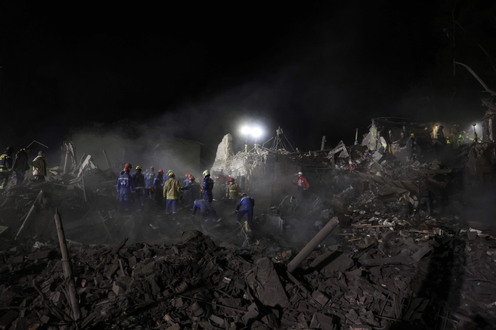 Ukrainian rescuers operate at the site of a Russian missile attack in Kyiv early on April 24, 2025, amid the Russian invasion of Ukraine. (Photo by STRINGER / AFP)