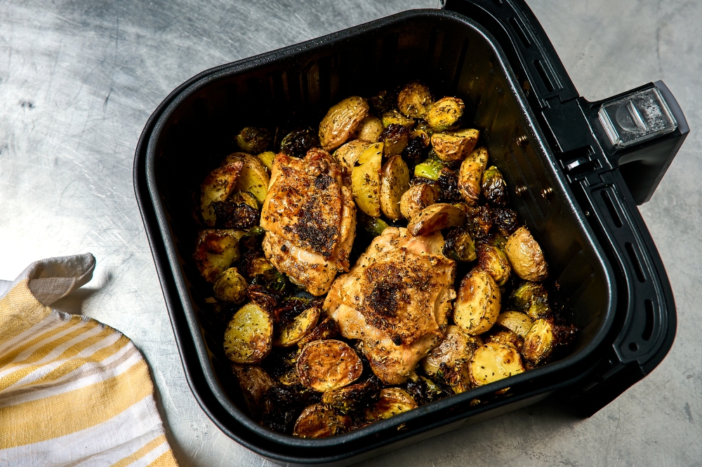 File: Air fryer chicken thighs with potatoes and Brussels Sprouts. (Photo by Peggy Cormary for The Washington Post)