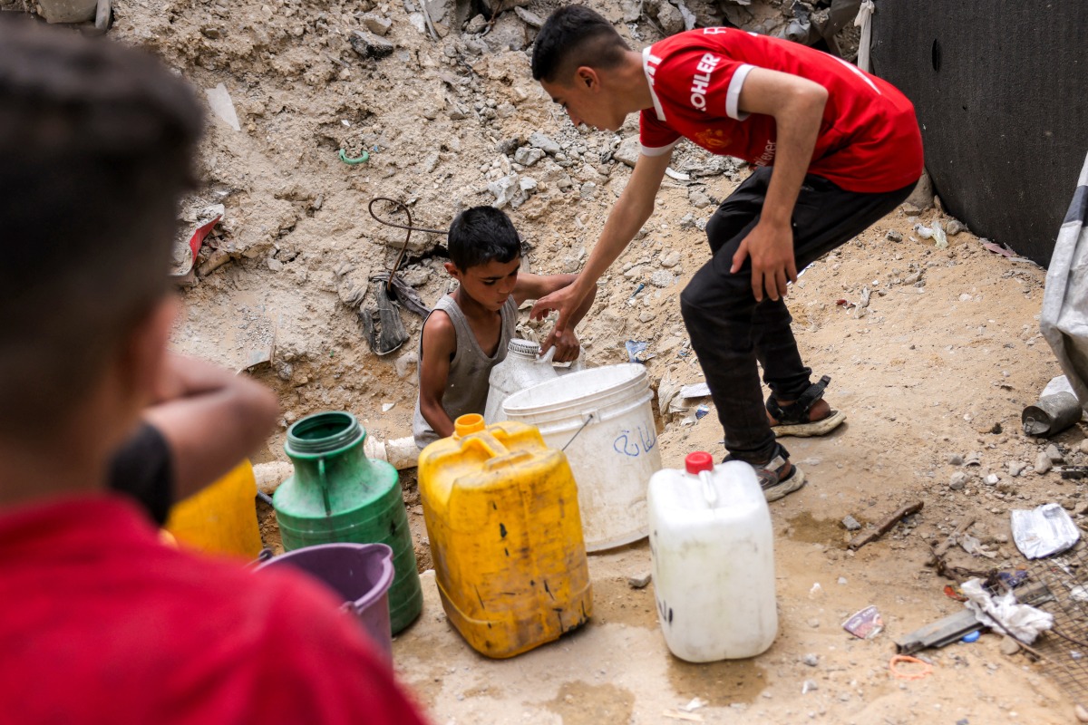 A boy fills up containers with water from the remaining water still left in underground pipes, in Beit Lahia in the northern Gaza Strip on April 24, 2025. Photo by Bashar Taleb/ AFP