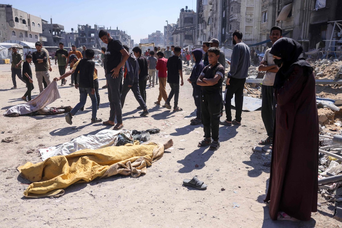 Graphic content / Palestinian stand over the shrouded bodies of people killed during an Israeli drone strike in Jabalia, in the northern Gaza Strip on May 23, 2025 (Photo by Bashar TALEB / AFP)
