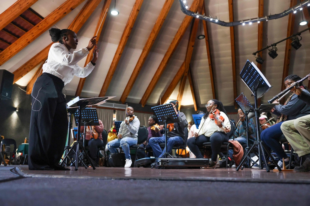 (Files) South African conductor Ofentse Pitse (L) waves her conducting baton during rehearsals at Marks Park Sports Club in Johannesburg on June 4, 2024. (Photo by Phill Magakoe / AFP)