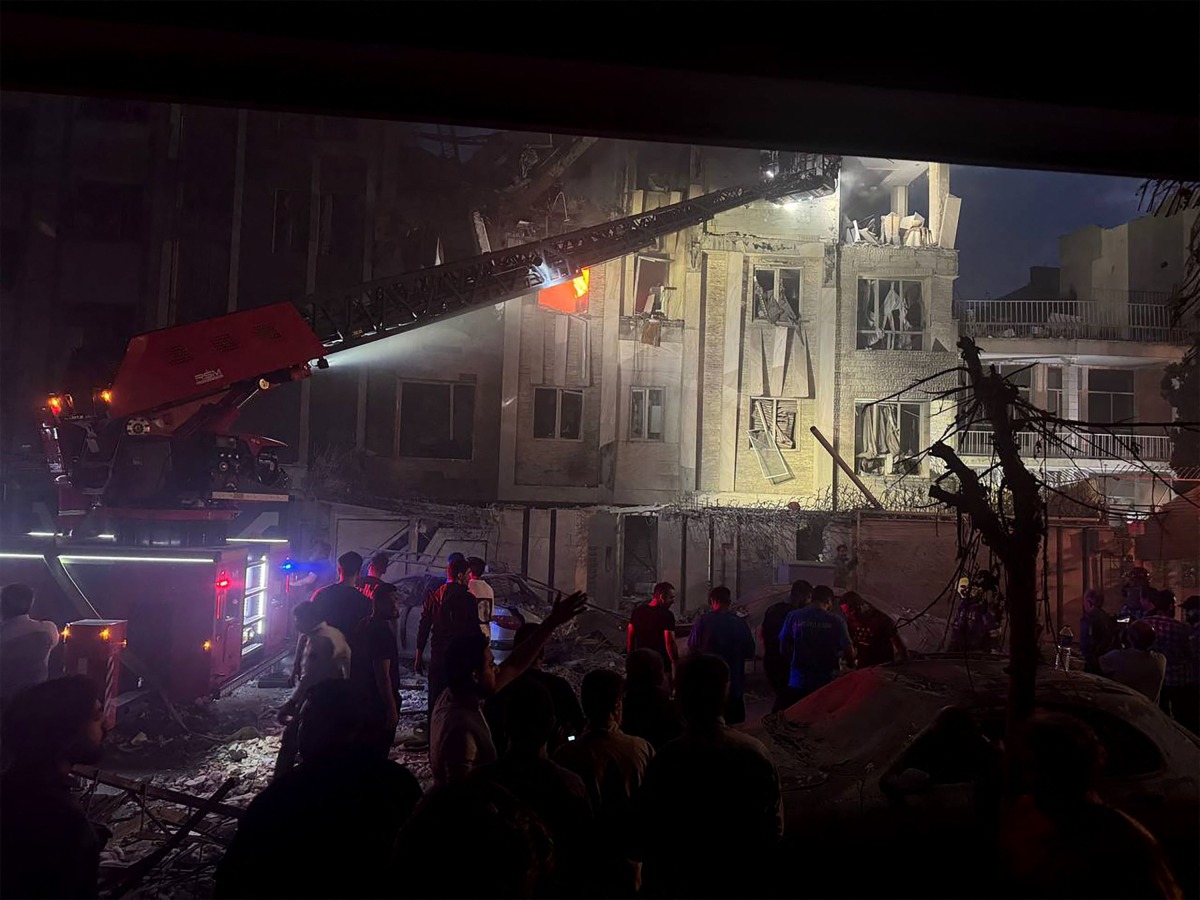 This handout photo released by Iran's Revolutionary Guard Corps (IRGC) official Sepah News Telegram channel on June 13, 2025 shows onlookers and rescue teams in front of a building that caught fire following and Israeli strike on the Iranian capital Tehran early in the morning. (Photo by SEPAH NEWS / AFP)