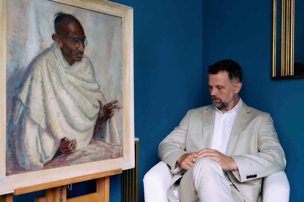 Caspar Leighton, great-nephew of British-American artist Clare Leighton, poses with a painting by his great-aunt of Indian independence leader Mahatma Gandhi at Bonhams auction house in London on June 9, 2025. (Photo by Benjamin Cremel / AFP)

