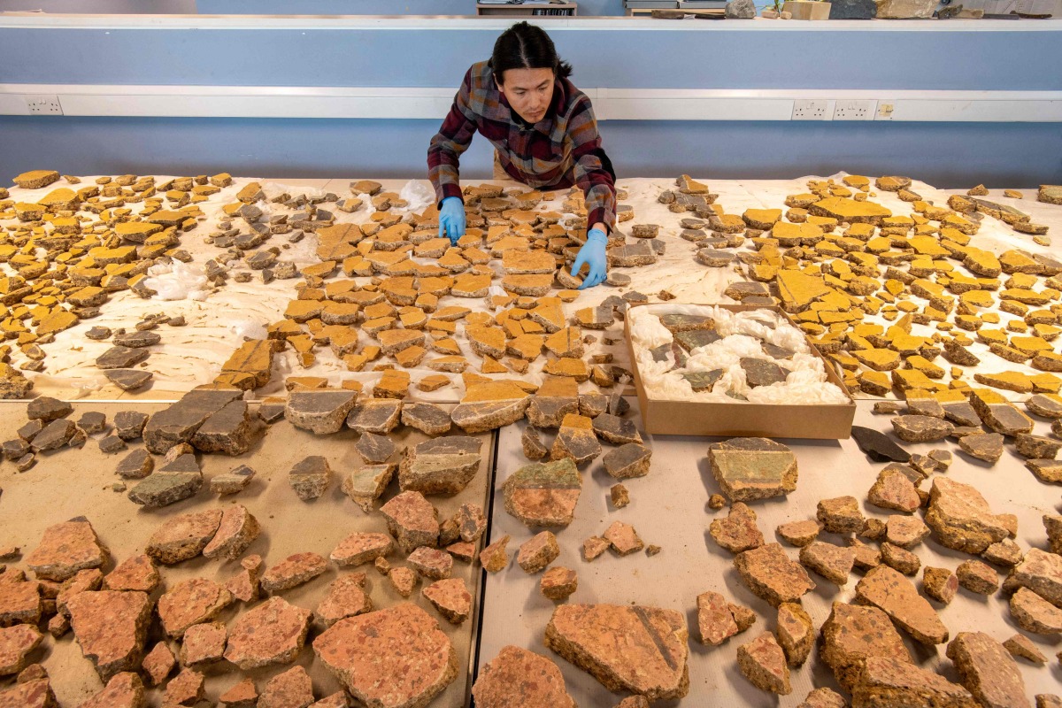 A handout picture released by the Museum of London Archaeology (MOLA) on June 19, 2025 shows MOLA senior building material specialist Han Li laying out Roman plaster fragments from The Liberty development site in Southwark, south London. Photo by Handout / Museum of London Archaeology (MOLA) / AFP