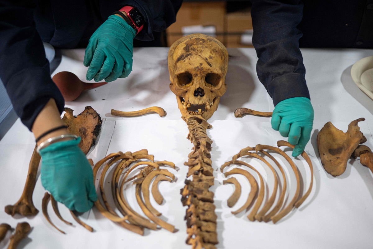 Experts work around the remains of a pre-Hispanic burial that was found during an excavation to install a gas pipeline in Lima on June 19, 2025. Photo by Ernesto BENAVIDES / AFP