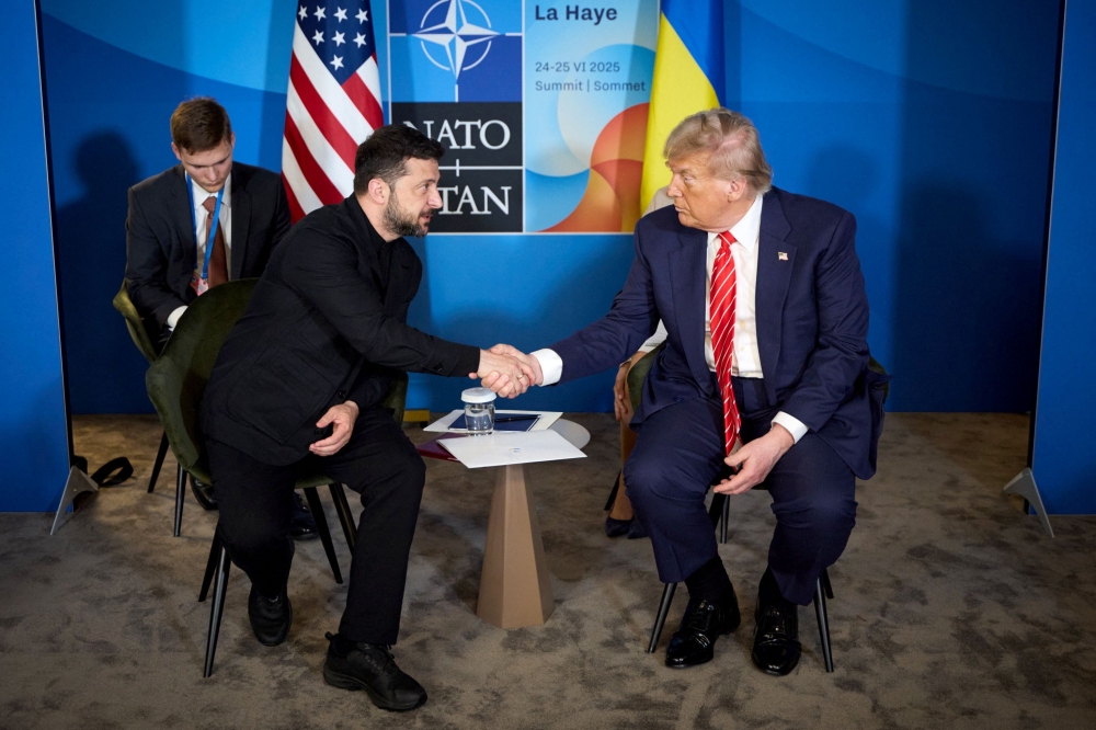In this handout photograph taken and released by the Ukrainian Presidential Press Service on June 25, 2025, Ukraine's President Volodymyr Zelensky (left) shakes hands with US President Donald Trump during their meeting on the sideline of the North Atlantic Treaty Organization (NATO) summit in The Hague. (Photo by Handout / AFP)
