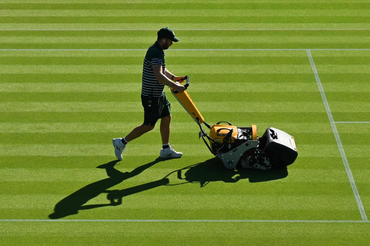 A member of the groundstaff mows the grass on a court on the first day of the 2025 Wimbledon Championships at The All England Lawn Tennis and Croquet Club in Wimbledon, southwest London, on June 30, 2025. (Photo by Glyn KIRK / AFP)