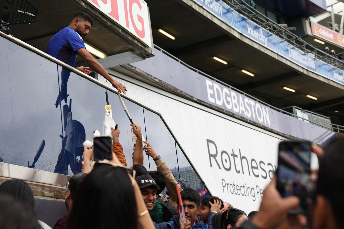 India's non-playing bowler Jasprit Bumrah signs autographs for fans, as rain delays the start of play on day five of the second cricket test match between England and India at Edgbaston cricket ground in Birmingham, central England on July 6, 2025. (Photo by Darren Staples / AFP) 