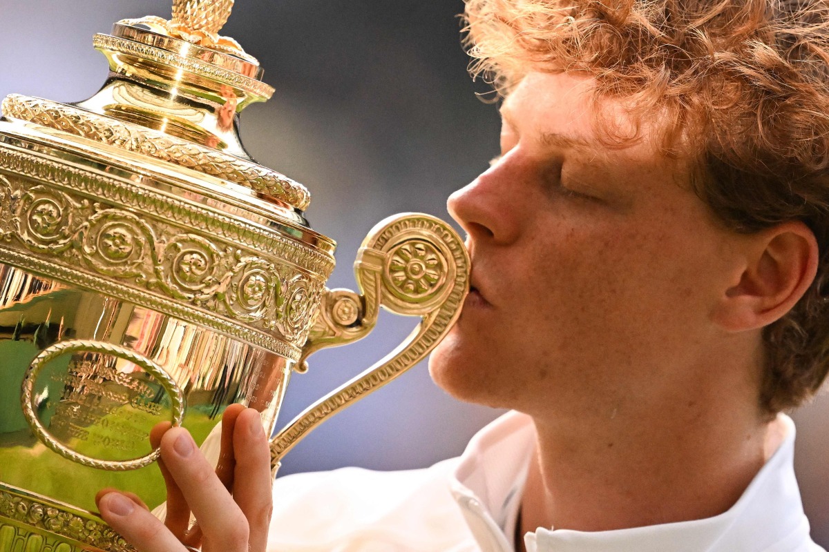 Italy's Jannik Sinner kisses the winner's trophy as he poses for pictures following his victory against Spain's Carlos Alcaraz at the end of their men's singles final tennis match on the fourteenth day of the 2025 Wimbledon Championships at The All England Lawn Tennis and Croquet Club in Wimbledon, southwest London, on July 13, 2025. (Photo by Kirill KUDRYAVTSEV / AFP) / RESTRICTED TO EDITORIAL USE
