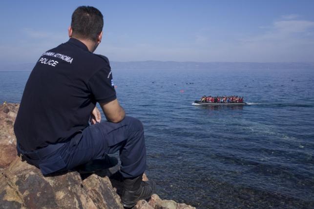A Greek police officer looks at an overcrowded dinghy carrying refugees and migrants arriving. Reuters. File photo for representational purposes only.