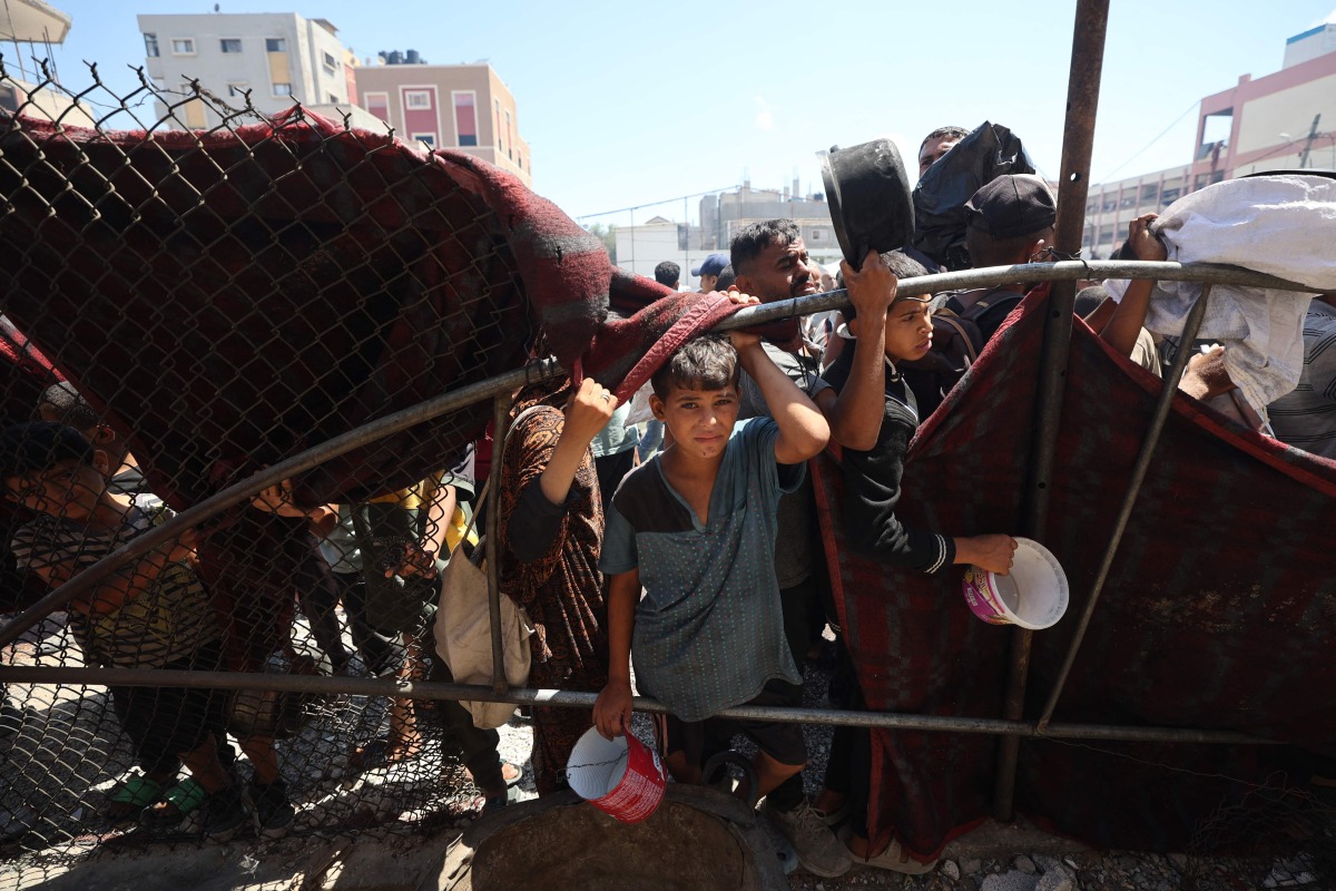 Palestinians gather at a food distribution point in the Nuseirat refugee camp in the central Gaza Strip on July 19, 2025. (Photo by Eyad BABA / AFP)
