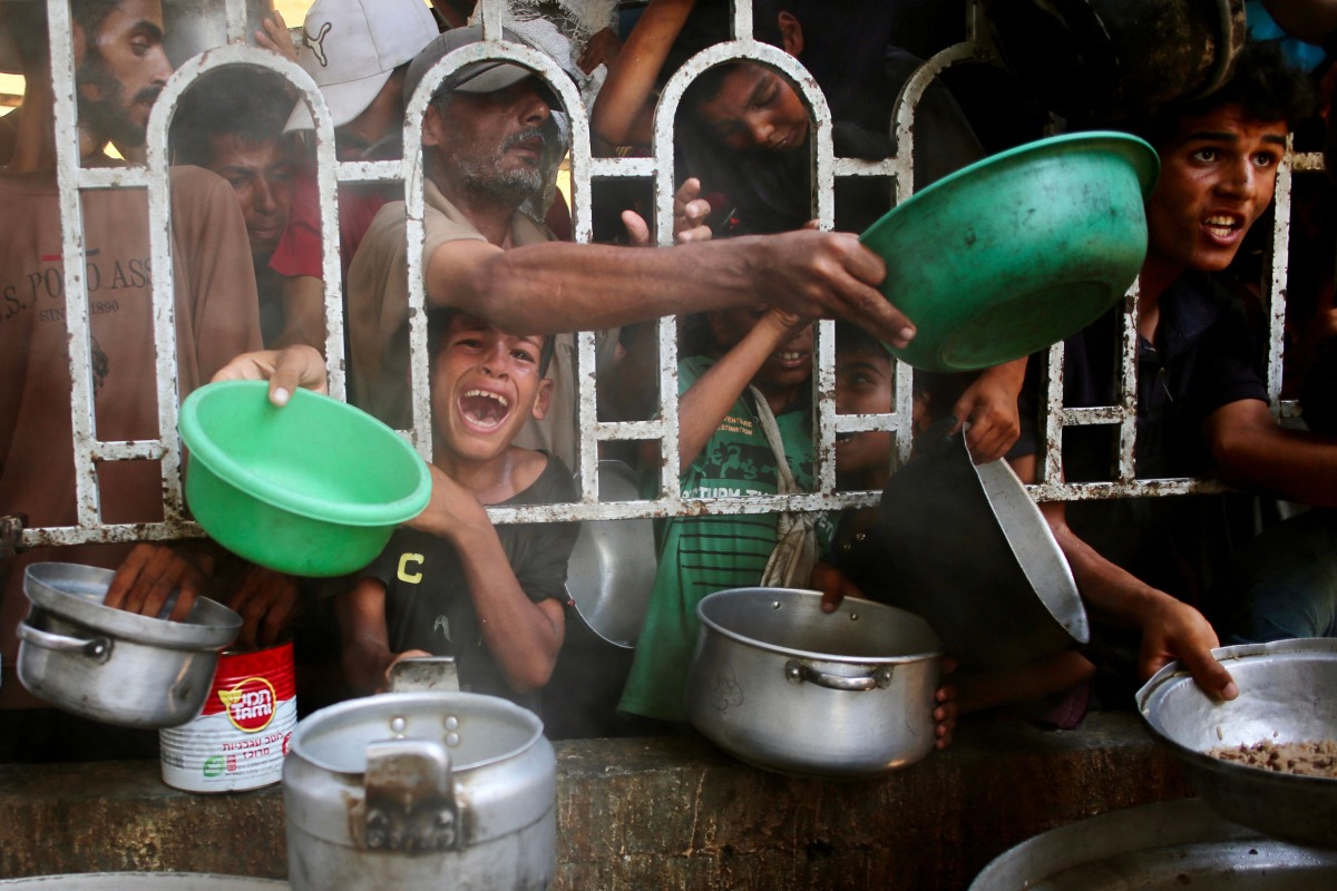 Palestinians shove to receive a hot meal at a charity kitchen in the Mawasi area of Khan Yunis in the southern Gaza Strip on July 22, 2025. Photo by AFP