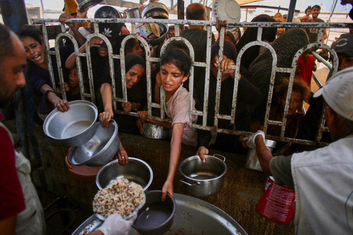 Palestinians queue to receive a hot meal at a charity kitchen in the Mawasi area of Khan Yunis in the southern Gaza Strip on July 22, 2025. (Photo by AFP)
