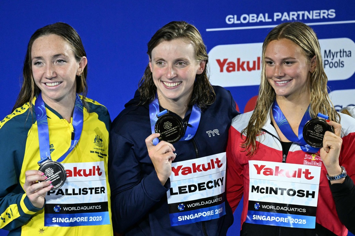 (L-R) Silver medallist Australia's swimmer Lani Pallister, gold medallist US' swimmer Katie Ledecky and silver medallist Canada's swimmer Summer McIntosh pose on the podium of the women's 800m freestyle swimming event during the 2025 World Aquatics Championships in Singapore on August 2, 2025. (Photo by Oli SCARFF / AFP)
