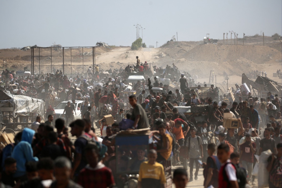 Palestinians leave a food distribution point run by the US and Israeli-backed Gaza Humanitarian Foundation (GHF) group with bags and wooden pallets, near the Netsarim corridor in the central Gaza Strip on August 3, 2025. Photo by Eyad BABA / AFP