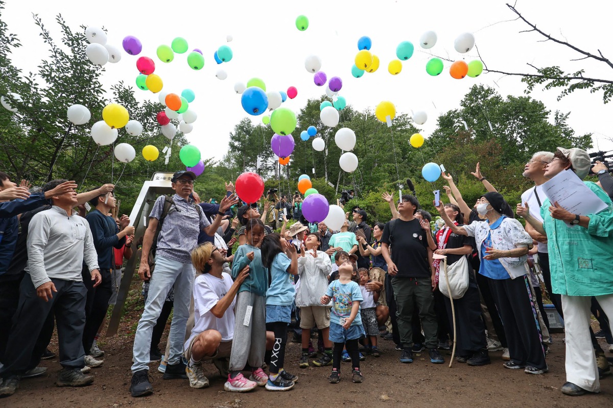 People release balloons to pray for the victims of the Japan Airlines Flight 123 crash, the world's deadliest single-aircraft accident with 520 killed, at the crash site on Mount Osutaka in Ueno Village, Gunma Prefecture on August 12, 2025. (Photo by JIJI Press / AFP) / Japan OUT