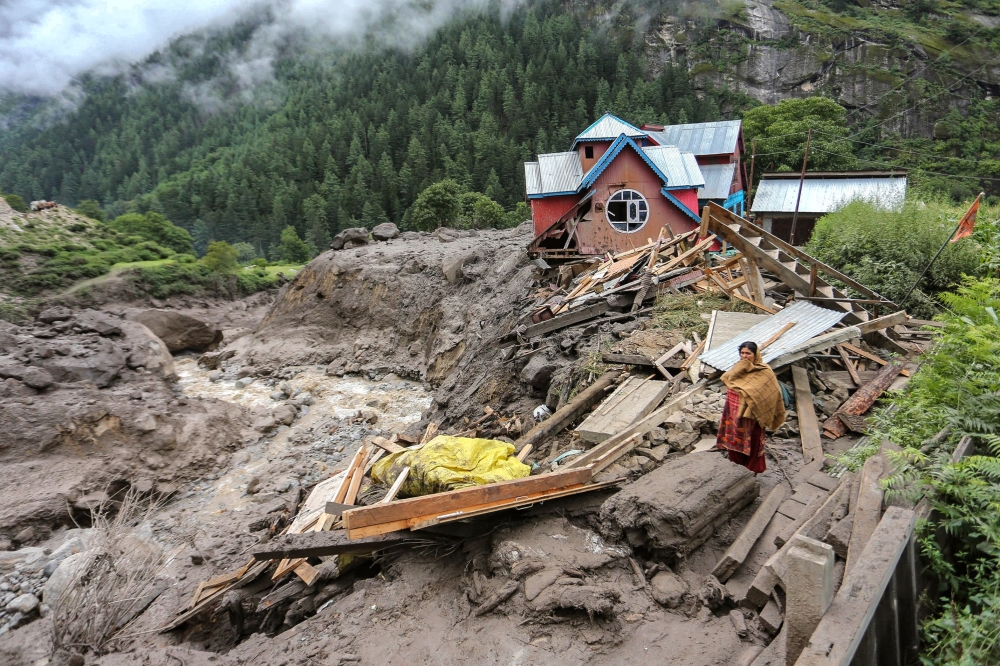 A woman looks on as she stands near a damaged house at the site of a flashflood at a village in Kishtwar district on August 15, 2025. Photo by Mir Imran / AFP)
