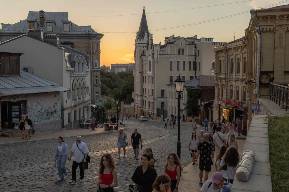 People walk on the Andriivskyi Descent in the Podil neighborhood, in downtown Kyiv, on August 16, 2025, amid the Russian invasion of Ukraine. (Photo by Roman Pilipey / AFP)