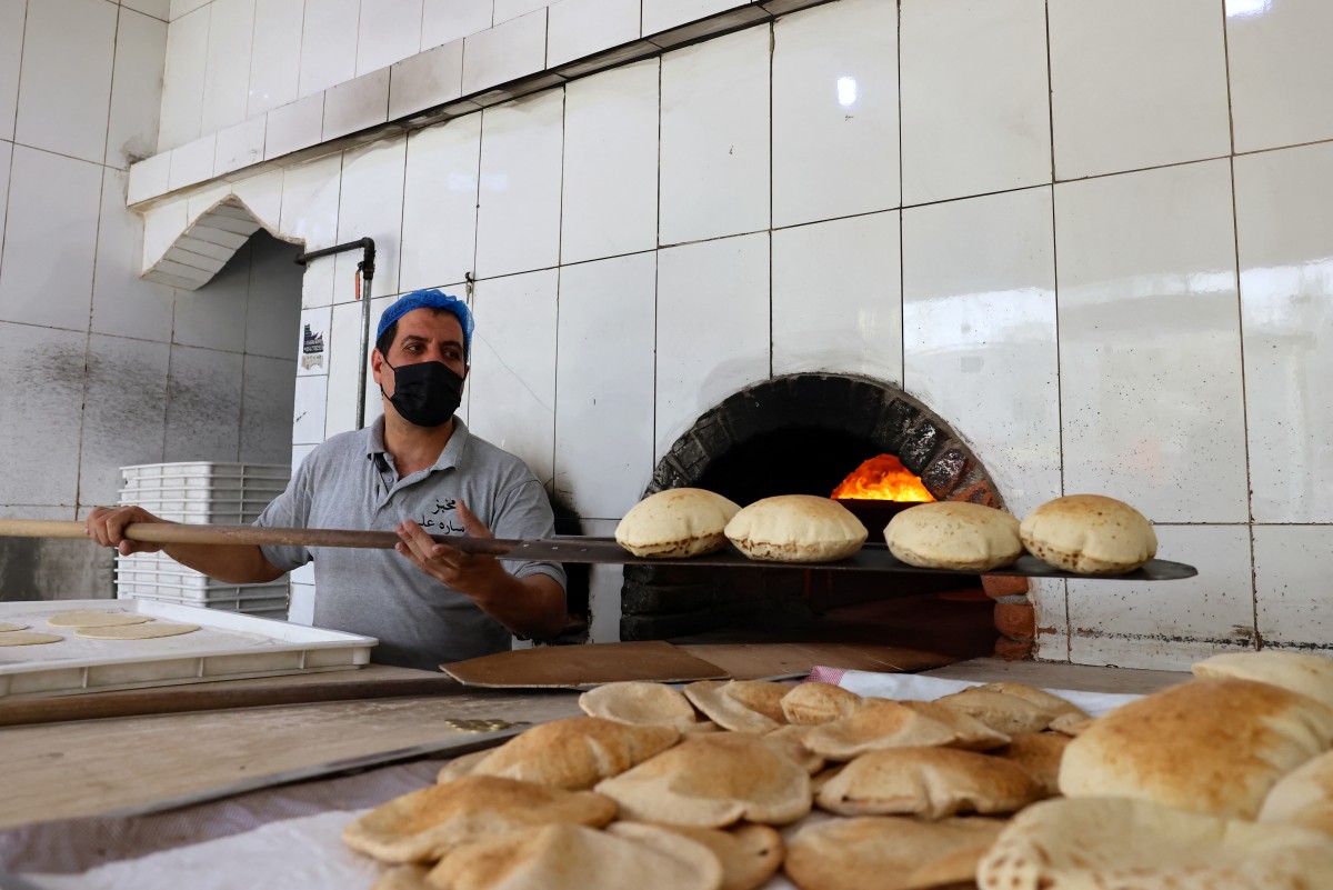 An Egyptian baker works in front of an oven at a bakery in Riyadh on August 14, 2025, during the soaring summer heat. (Photo by Fayez Nureldine / AFP)