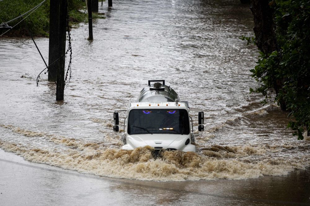 A truck drives through a flooded road as category 3 Hurricane Erin leaves the region in Naguabo, Puerto Rico on August 16, 2025. (Photo by Ricardo Arduengo / AFP)