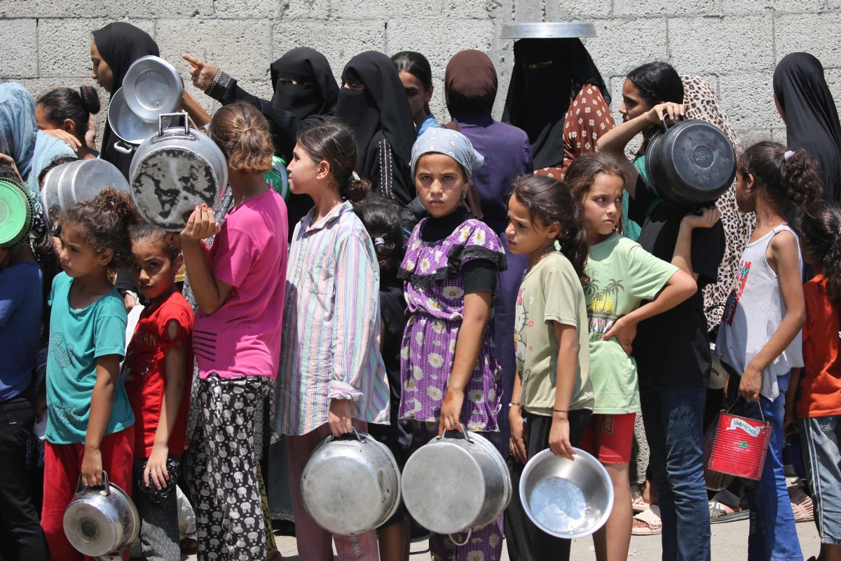 Palestinians gather to receive cooked meals from a food distribution center in the Nuseirat refugee camp in the central Gaza Strip on August 18, 2025. Photo by Eyad BABA / AFP